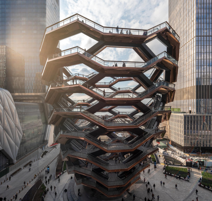 Foto do The Vessel, uma estrutura aberta com várias escadas em vários ângulos diferentes, se inclinando para a vertical formando um grande prédio com vários pontos de observação.